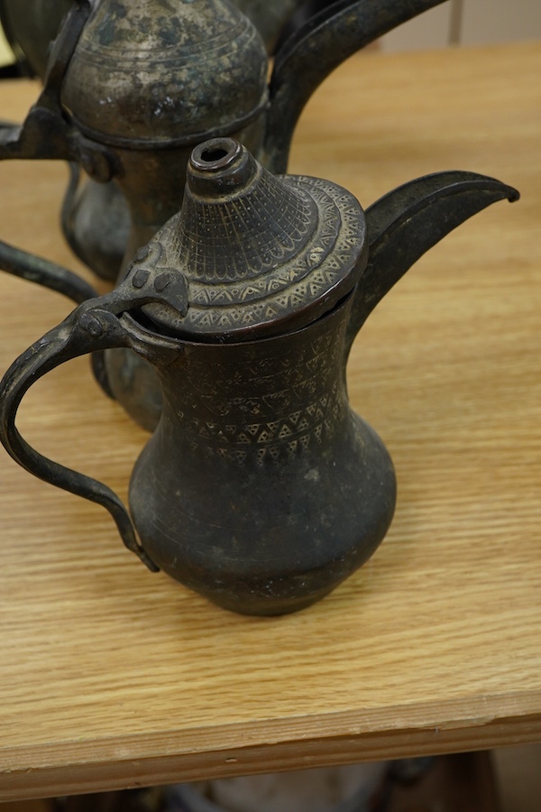 Three Arabic dallahs, two brass, one copper and a copper coffee ewer, 45cm
